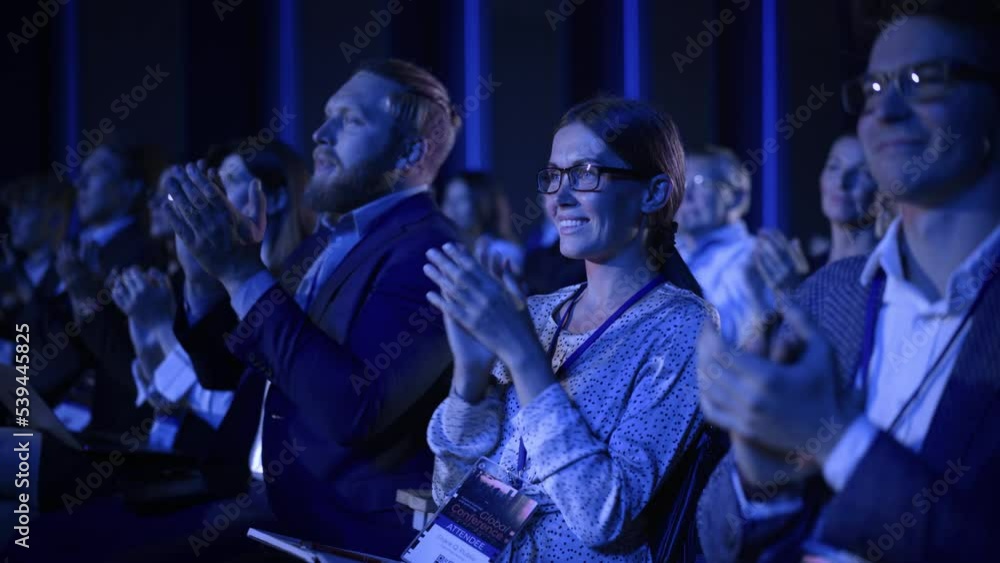 Young Female Sitting in a Crowded Audience at a Science Conference. Delegate Cheering and Applauding After an Inspirational Keynote Speech. Auditorium with Young Successful Specialist. Young Female Sitting in a Crowded Audience at a Science Conference. Delegate Cheering and Applauding After an Inspirational Keynote Speech. Auditorium with Young Successful Specialist.