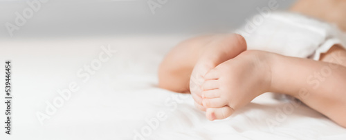 The baby crawls on a white bed. Legs of a newborn look straight © Evgenia