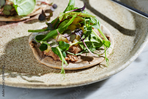 Rye tacos with duck confit, sliced pear and assorted microgreens photo