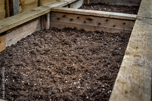 Wallpaper Mural Closeup of big wooden planter vegetable box container in garden filled with soil ready for planting seeds and plants. Torontodigital.ca