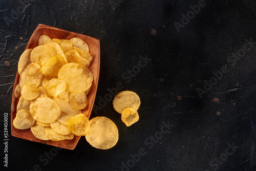 Potato chips or crisps in a bowl, shot from above on a black background with a place for text