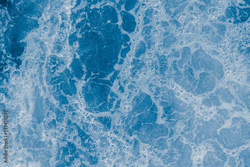 Abstract blue sea water with white foam and bubbles for background, natural summer background