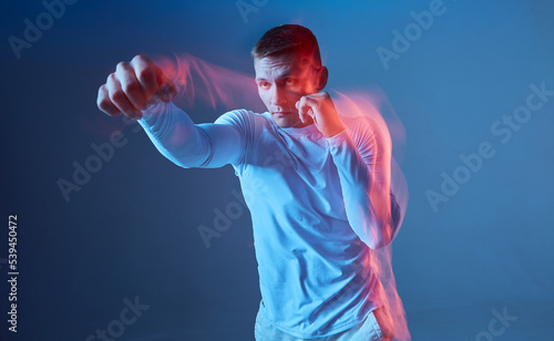 Strike by the right hand. Boxer in white rashguard on blue background.  © Georgii