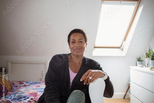 Portrait confident mature woman in sunny bedroom