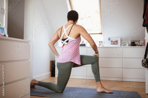 Woman exercising, practicing yoga twist on mat at home