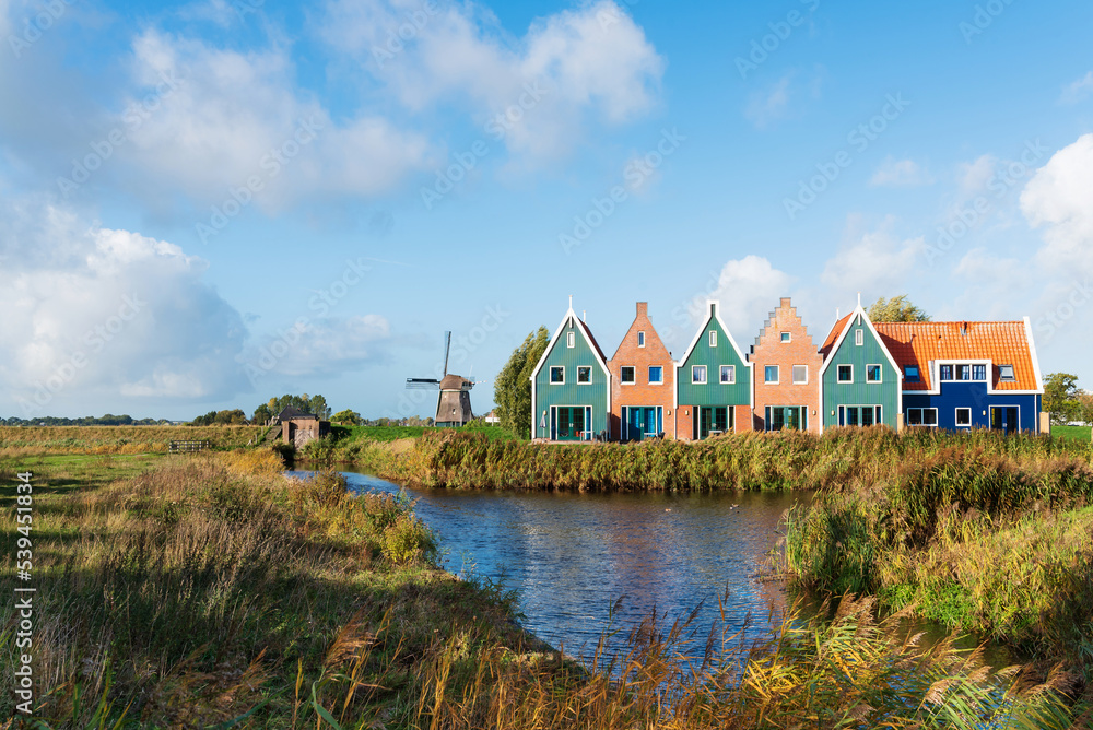 small colorful houses next to historic windmill in dutch town of Volendam, North Holland