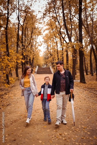 happy family with a child on an autumn walk in the city park walk along the alley, family fun © Anna