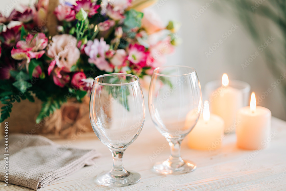 Festive dinner. Celebration table setting with flowers and candles. Beautiful table with glasses for drink and cozy flame lights. Romantic evening details Festive dinner. Celebration table setting with flowers and candles. Beautiful table with glasses for drink and cozy flame lights. Romantic evening details