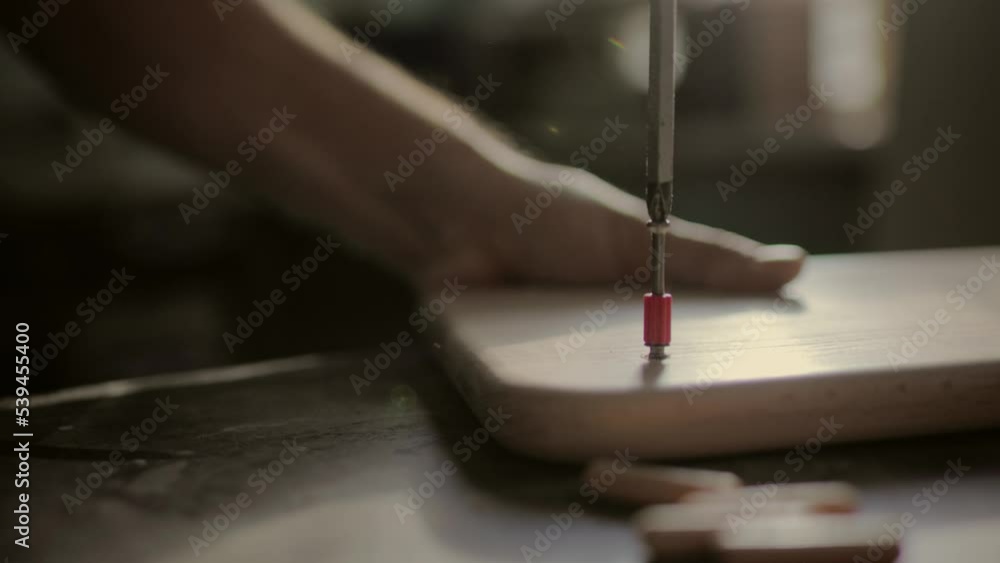 Screwing dowels into a wooden board. Production of children's furniture and educational games. Screwing dowels into a wooden board. Production of children's furniture and educational games.