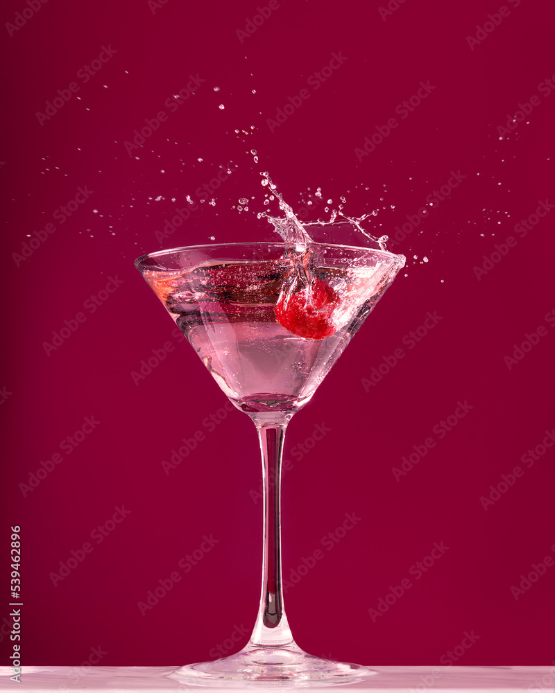 Raspberry splash in a martini cocktail glass on red background Raspberry splash in a martini cocktail glass on red background