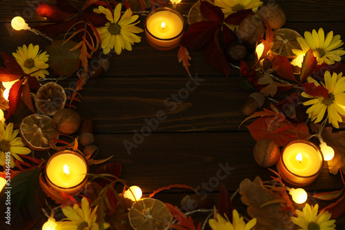 dark rustic wooden background with candles, autumn leaves and copy space