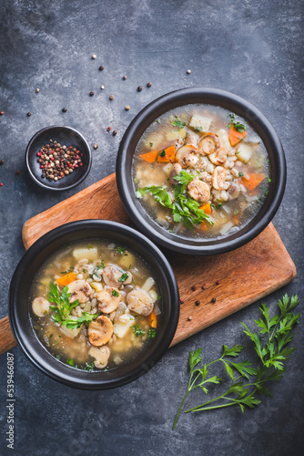 Mushrooms transparent  soup with champignon, vegetables and pearl barley. Simple and hearty cuisine for the cold season. Forest food, vegan proteins. Baltic cuisine