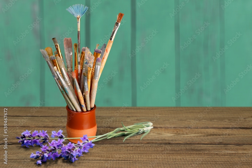 Set of paint brushes and lavender flower on desk