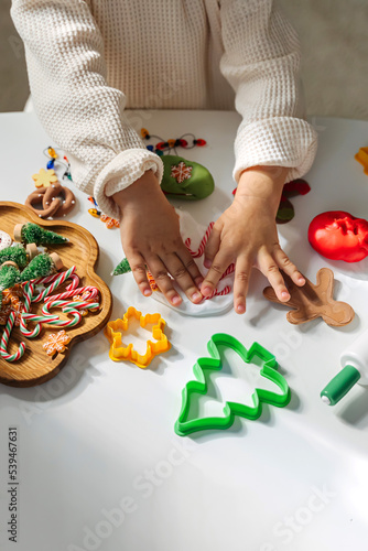 Child hands creating Christmas crafts. Child playing with play dough and Christmas decorations. Holiday Art Activity for Kids. Sensory play for toddlers.