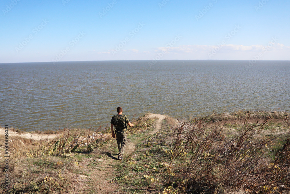 man walking towards a cliff over the lake