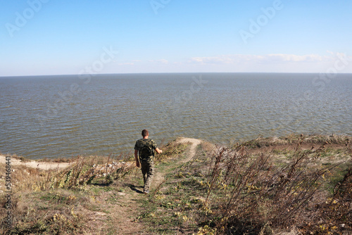 man walking towards a cliff over the lake