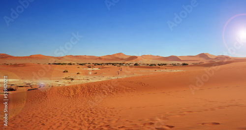 Landscape view from Dead Vlei in Namib Desert. There are people in the far distance returning to their vehicles after the long and hot walk to see the dunes and salt pan. 