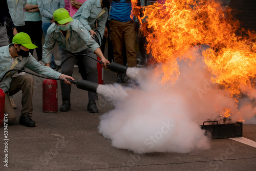 The trainees used a carbon dioxide fire extinguisher to extinguish a fire leaking at the valve of the cooking gas tank. Event of fire fighting and fire drill training.