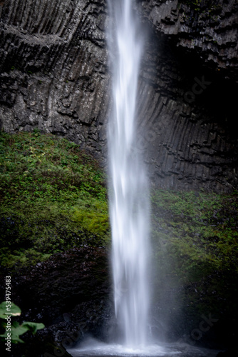 Latourell Waterfall in Oregon, with gray textured rock face and moss growing along the end of the waterfall. 