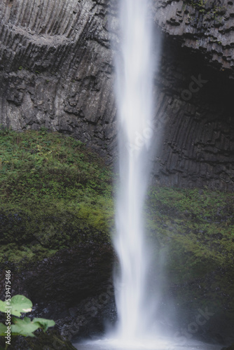 Latourell Waterfall in Oregon, with gray textured rock face and moss growing along the end of the waterfall. 