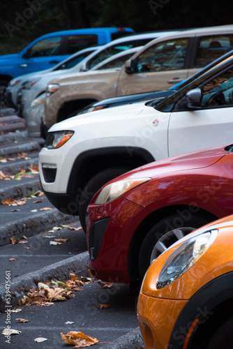 A row of cars with different colors and models lined up at a parking lot. 