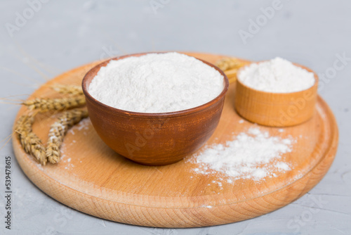 Flat lay of Wheat flour in wooden bowl with wheat spikelets on colored background. world wheat crisis