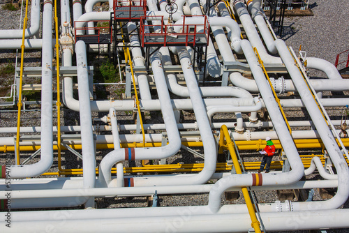 Top view male worker inspection at steel long pipes and pipe elbow valve in station oil factory during refinery valve of visual check record pipeline oil