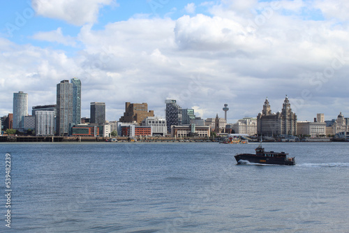 A beautiful image of the famous Liverpool Skyline and cityscape with the River Mersey in front. A speed boat and the ferry can be seen on the River.