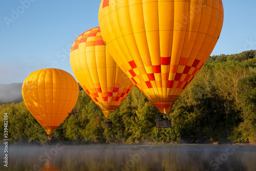hot air balloons fly low over dordogne river in southern france photo