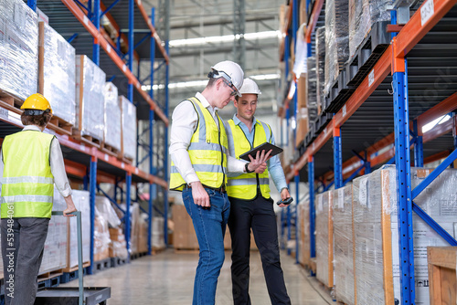 Worker in warehouse hold tablet check list perform inventory stock check goods boxes on the storage steel racking for annual report