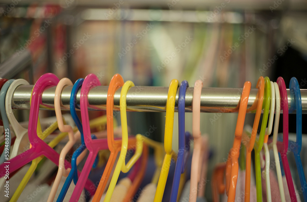 Some colorful plastic hangers lined up on a pole selective focus