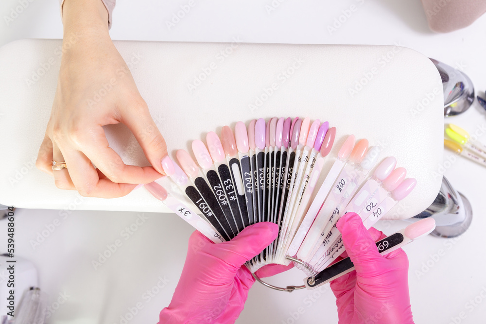Fototapeta premium Professional manicurist showing colorful nail polish to check the finish result.