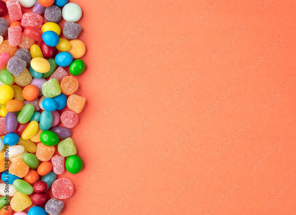 Obraz premium Colorful candies over orange background with copy space
