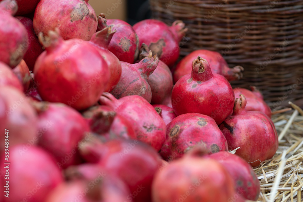 Harvest of ripe pomegranate on dry straw at outdoor farmers market in Tbilisi Georgia. Vegetarian healthy food Harvest of ripe pomegranate on dry straw at outdoor farmers market in Tbilisi Georgia. Vegetarian healthy food