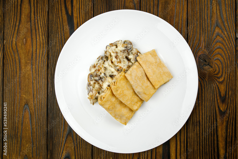 delicious pancakes with fried mushrooms on a plate.
delicious pancakes with fried mushrooms on a plate.