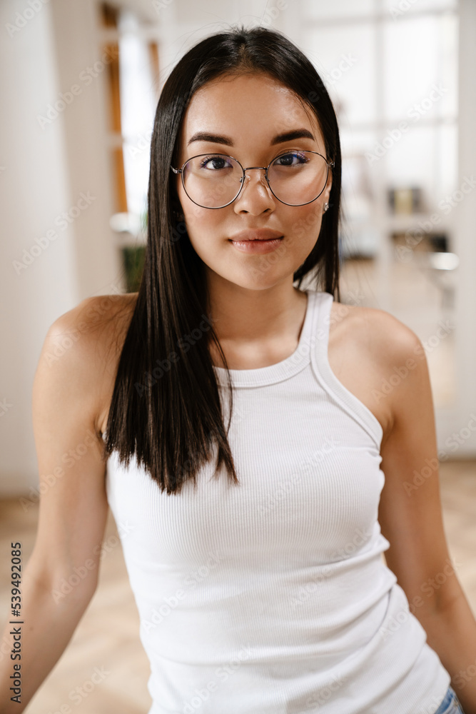 Young beautiful calm asian woman in glasses looking at camera