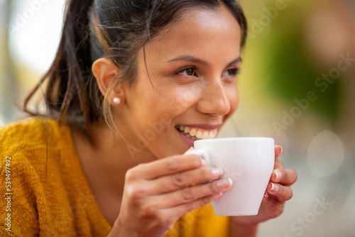 Close up smiling young woman drinking cup of coffee