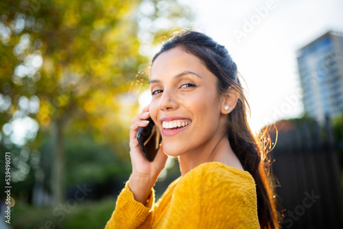 Close up smiling woman talking with cellphone in park