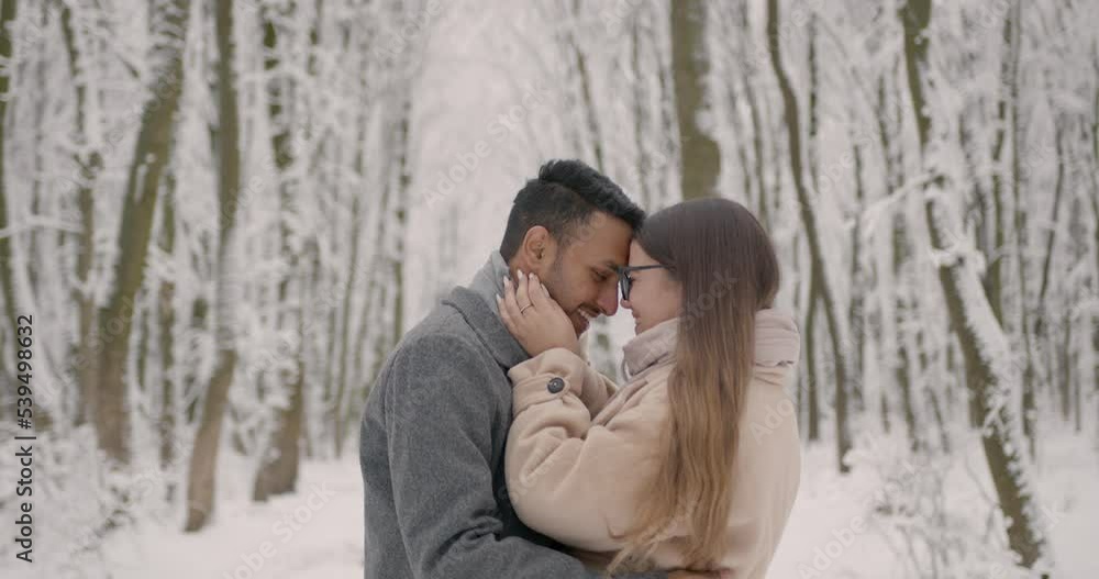 Multiethnic couple hugging each other in winter forest Multiethnic couple hugging each other in winter forest