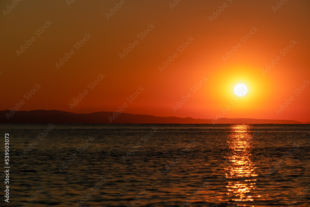 Panoramic view of sunset over Aegean Mediterranean Sea seen from Karydi beach, peninsula Sithonia, Chalkidiki (Halkidiki), Greece, Europe. Romantic atmosphere, reflection of the sunbeams on surface