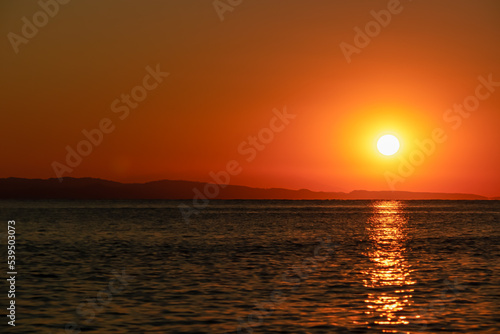 Panoramic view of sunset over Aegean Mediterranean Sea seen from Karydi beach, peninsula Sithonia, Chalkidiki (Halkidiki), Greece, Europe. Romantic atmosphere, reflection of the sunbeams on surface © Chris