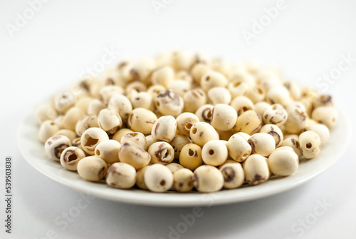 Dried lotus seeds in white plate on white background, selective focus.