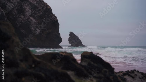 Ocean wild beach stormy weather in dusk time. Praia da Adraga sandy beach with picturesque landscape background, Sintra Cascais, Portugal. 