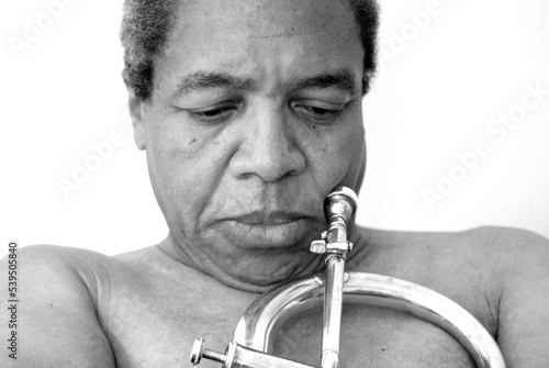 African american jazz musician holding his flugelhorn indoors.