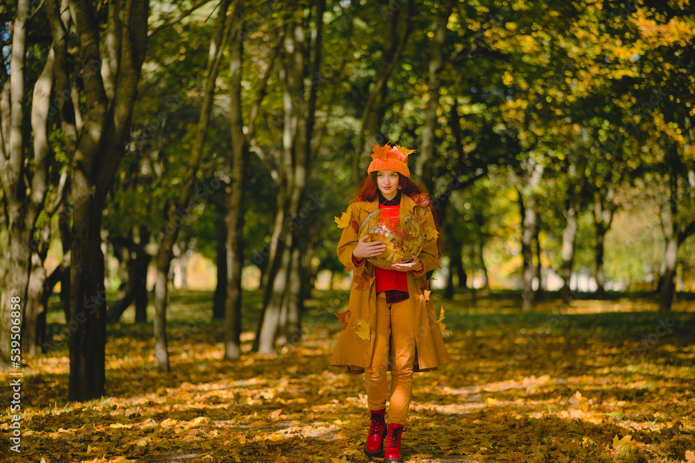 girl walks through the autumn park and holds an aquarium with leaves in her hands. girl walks through the autumn park and holds an aquarium with leaves in her hands.