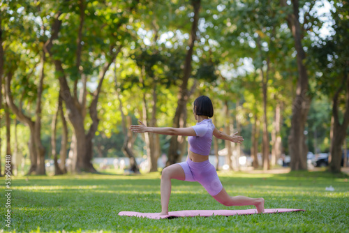 Yoga in the park. Young Asian woman practicing yoga pose at the park. © amnaj