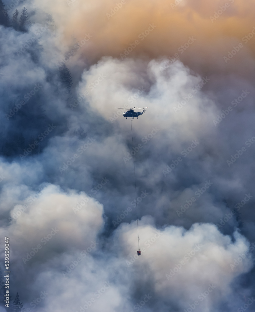 Wildfire Service Helicopter flying over BC Forest Fire and Smoke on the mountain near Hope during a hot sunny summer day. British Columbia, Canada. Natural Disaster Wildfire Service Helicopter flying over BC Forest Fire and Smoke on the mountain near Hope during a hot sunny summer day. British Columbia, Canada. Natural Disaster