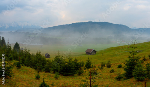 Small cabin on mountain meadow at forest edge, Geroldsee in the background Karwendel Mountains at sunrise, Kaltenbrunn, Upper Bavaria, Germany photo