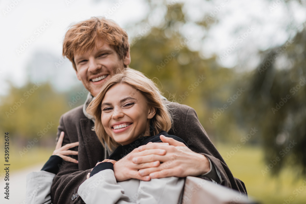 Fototapeta premium cheerful young man hugging positive woman in green park.