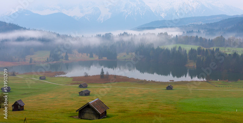 Small cabin on mountain meadow at forest edge, Geroldsee in the background Karwendel Mountains at sunrise, Kaltenbrunn, Upper Bavaria, Germany photo